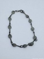 Close-up image of the sterling silver tennis racquet-shaped link bracelet with lobster clasp against a white background.