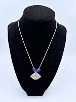 Sterling silver Tibetan pendant necklace on black display bust, showing cobalt blue beads and chain.