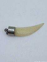 Front view of a 2 inch natural tooth pendant with silver cap and loop.