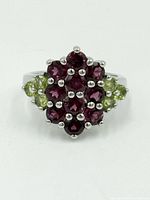 Top close-up of the ring face showing oval cluster of red tourmalines and green peridots on polished sterling silver band.