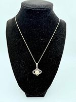 Full view of necklace displayed on black velvet bust showing silver chain and pendant with pearl and sapphire stones.