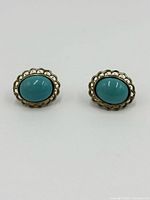 Front view of turquoise earrings showing oval turquoise stones with gold-tone scalloped bezel.