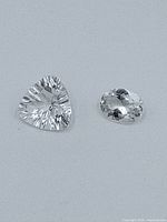 Two white sapphire gemstones on plain background showing shape and clarity