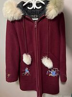 Front view of the burgundy wool coat with fur-lined hood and patches on pockets and sleeves
