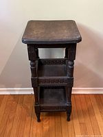 Front view of vintage wooden side table showing all three shelves and carved apron details.
