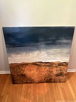 Front view of the square canvas painting showing abstract landscape with dark sky and earthy ground, painted on stretched canvas.