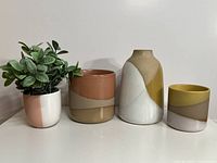 Front view of four ceramic pieces showing colors and plant