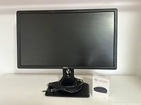 Front of Dell 24-inch LCD monitor with coiled HDMI cable on the base and boxed wireless mouse next to it.