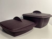 Two burgundy silicone containers with fitted lids, showing overall shape and size difference.