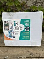Front of the box showing product images and features like steel frame, foam grip handle, heavy-duty wheels, and garden tools in use.