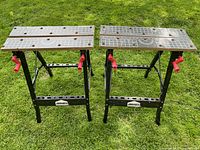 Overview of two Jobmate foldable sawhorses with black metal frames, grey grid surface tops with measurement markings, and red handles.