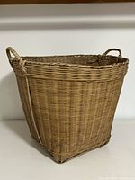 Side view of large natural wicker hamper showing woven texture and handle.
