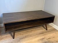 Full view of rectangular Mid-Century Modern wooden coffee table with open storage space underneath and four tapered legs.