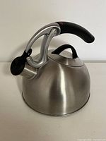 OXO stainless steel kettle showing side profile with black handle and uplift spout closed.