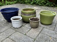 Photo of all five planters arranged on brick surface, showing mixed colors and sizes