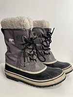 Side view of the grey Sorel winter boots showing fleece lining, lace-up front, and logos.