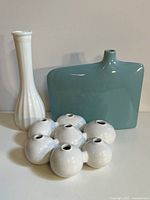 Front view of all three vases showing white tall vase, blue ceramic flat vase, and white propagation vase with seven holes.