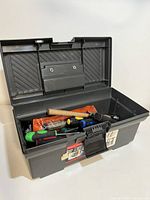 Black Rubbermaid toolbox open showing contents of assorted hand tools including screwdrivers, hammer, pliers, and other tools. Toolbox size approximately 7.5" tall and 16.5" long.