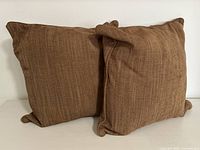 Pair of two brown textured square pillows angled to show shape and fullness