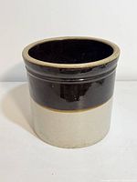 Front view of the stoneware crock showing two-tone brown and beige glaze and overall shape.