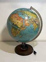 Front view of the illuminated globe showing a 12-inch diameter globe with wooden and metal construction and attached electric cord.