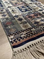 Close-up angled photo showing texture, edge design, and cream-colored fringed tassels on the rug