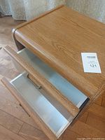 Top and open drawers view showing wood grain veneer surface and white drawer interiors with metal handles.