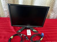 Front view of Acer X193W monitor on stand with power and VGA cables laid out in front on a red cloth background.