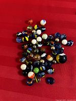 Photo of assorted glass marbles on a red surface showing various colors and designs