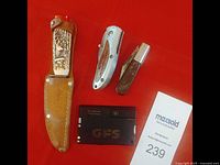 Photo showing 3 knives and Victorinox Swiss card multi-tool, seller's lot card showing maximum lot number