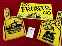 Two yellow foam fingers and a yellow promotional poster laid out on a red background, showing K-Rock Centre event branding.