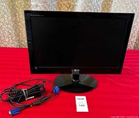 Front view of LG Flatron E2040 computer monitor on round base stand. Monitor screen is off. Power adapter and VGA cable coiled beside monitor.