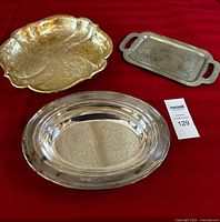 All three serving dishes arranged on red cloth: gold scalloped shell square dish, silver rectangular dish with handles, silver plated oval dish.
