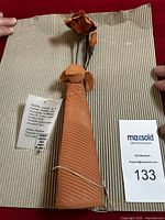 Full view of the terracotta clay flower pot standing with coiled thin stems and three clay flowers.