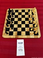 Top view of wooden chess board with black and natural wood chess pieces set up in starting position