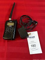 Full view of Uniden NASCAR Scanner BC72XLT with charging cord on red background