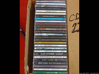 Stack of 27 CD jewel cases showing spine labels with artist and album titles from country, rock, jazz, and crooner genres.