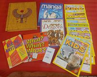 Photo showing full set of books and magazines including Egyptology interactive book with Egyptian theme cover, manga drawing book, dragons book, question books, and National Geographic Kids magazines.