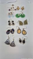 Photo showing all 10 pairs of sterling silver dangle earrings with multicolored stones arranged on white surface.