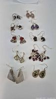 Photo of 10 pairs of sterling silver dangle earrings showing various colors and stone shapes laid on flat surface.