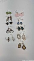 Photo showing all 10 pairs of sterling silver dangle earrings arranged on white surface