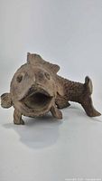 Front angled view of resin fish sculpture showing detailed face and fins in earthy brown color.