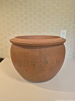 Side profile view of a vintage terracotta planter pot showing its rounded body and thick rim.