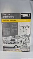 Image showing original packaging of Thule 962XT Speedway 3 trunk-mounted strap rack carrier, stating it holds 3 bikes and features a no-sway cage for added stability. Box includes image of rack mounted on a vehicle with 3 bikes.