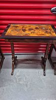 Full view of vintage wooden table showing decorative inlaid top and turned legs.