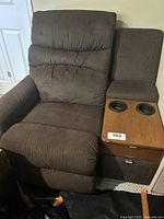 Brown fabric recliner chair with attached wooden side table featuring two cup holders.
