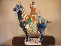 Front and side view showing warrior on horse sculpture with colorful details and base.