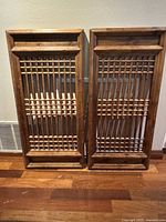 Two rectangular wood lattice art pieces side by side against wall on wooden floor, showing full view and proportions