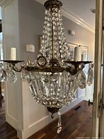 Full view of the antique crystal and brass chandelier with light holders and hanging crystal beads and pendants.