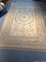 Full view of the French Aubusson needlepoint flatwave rug laid flat on a blue carpeted floor.